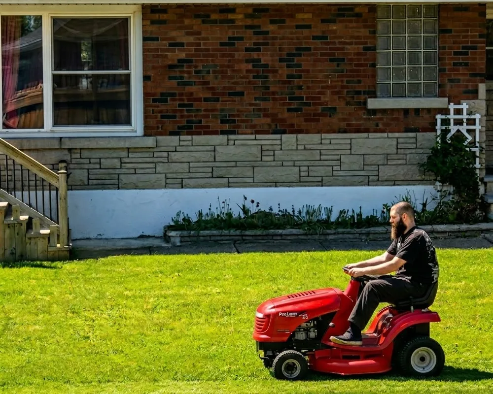 Austin, owner of 2boots, mowing a lawn in the Niagara region